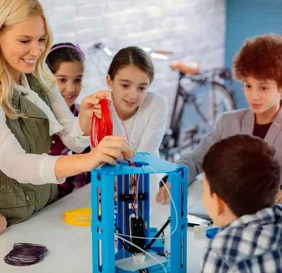Trainer and children assembling a 3D printer during a class